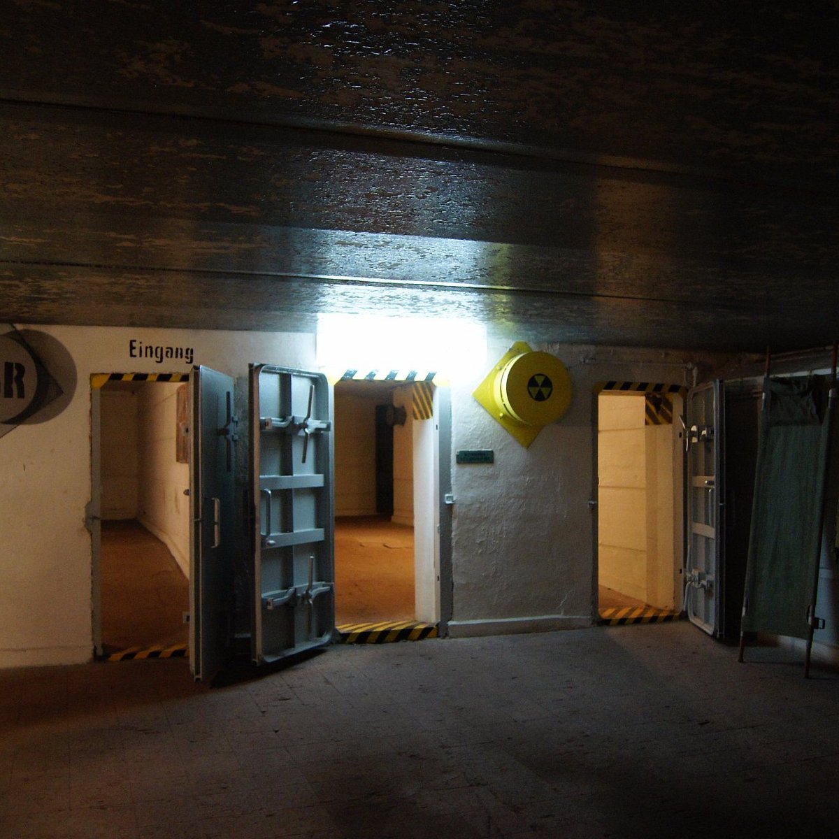 Grupa turystów stojących przed ruinami betonowego schronu Wału Pomorskiego w lesie